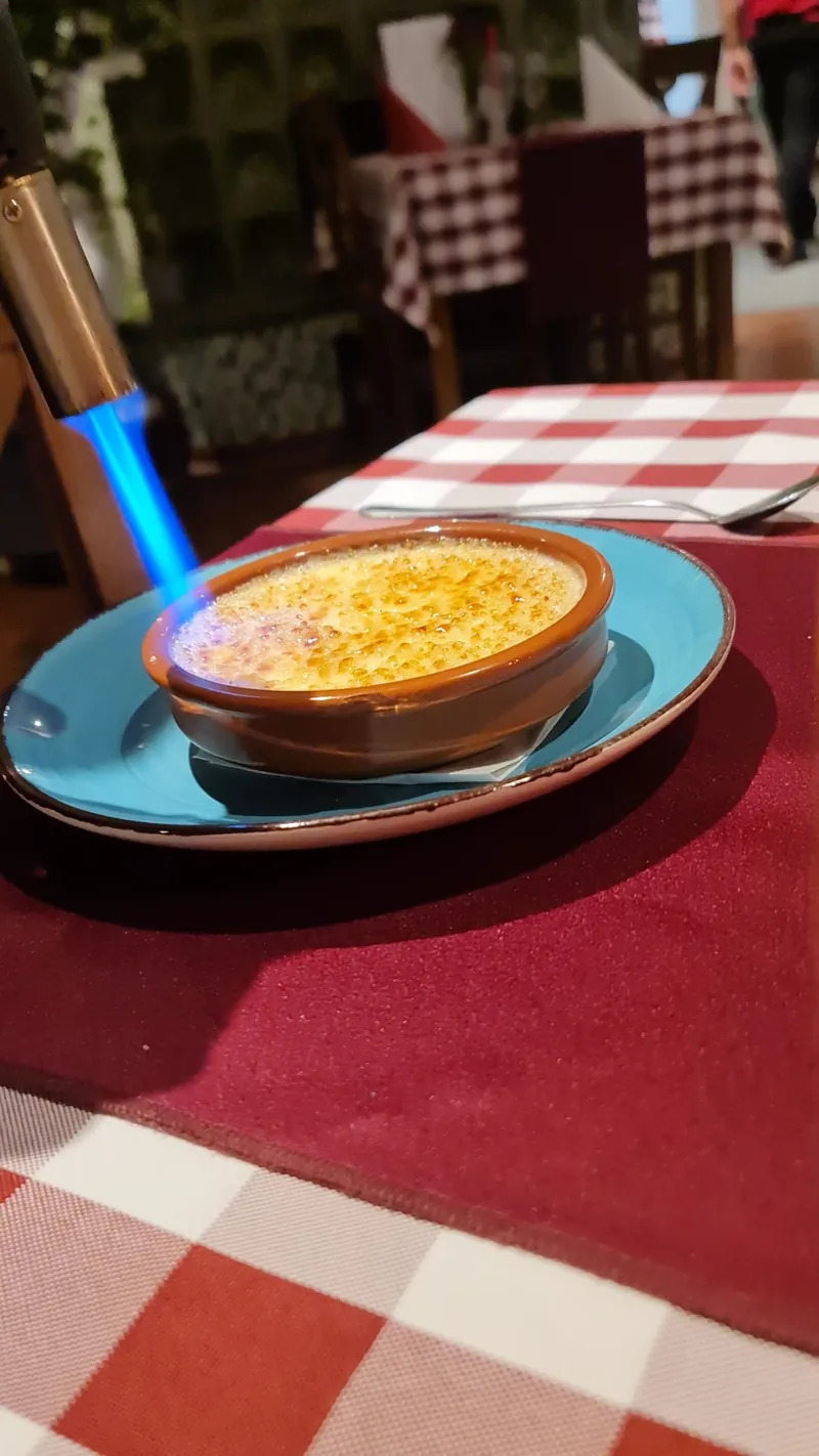 Crème brûlée wird am Tisch mit blauer Flamme karamellisiert