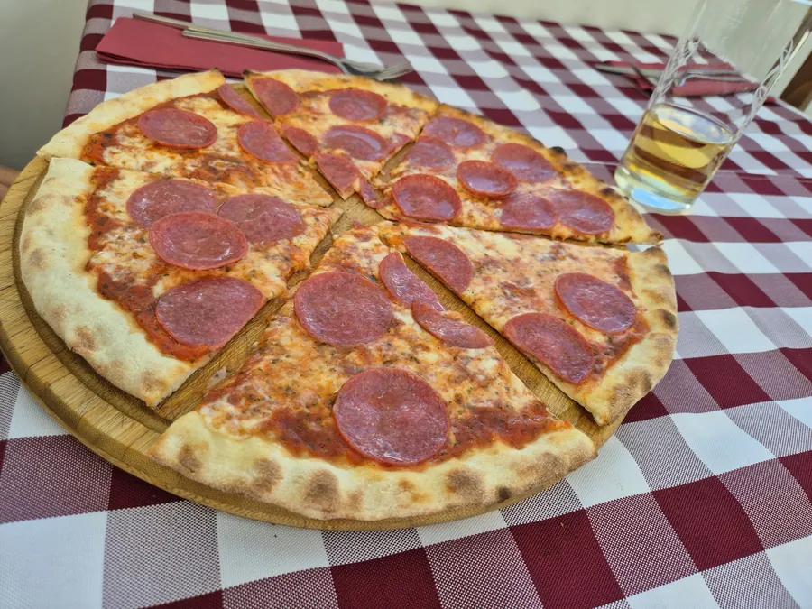 Pizza Salami aus dem Steinofen auf kariertem Tischtuch